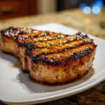 Two thick, juicy pork chops with dark grill marks and a shiny glaze, perfect results from a marinade for pork chops.