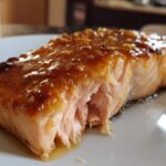 Close-up of a perfectly cooked, flaky salmon fillet topped with a sticky, sweet glaze and sesame seeds.