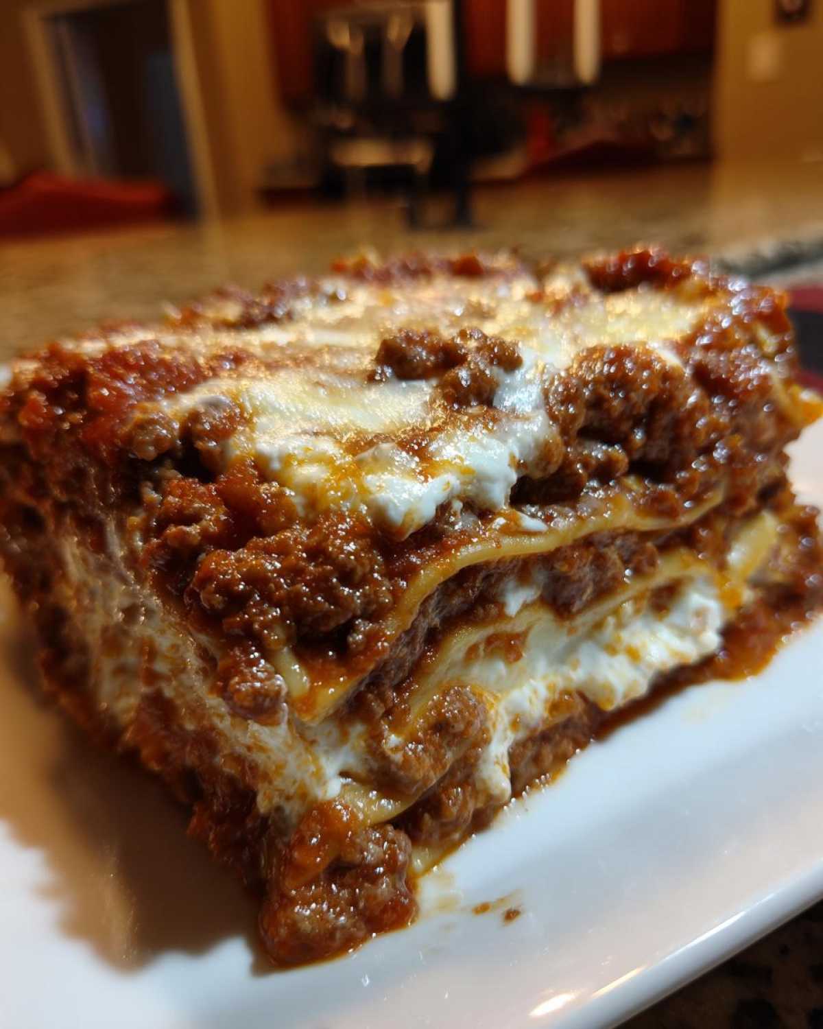 Close-up of a thick, layered slice of homemade lasagna showing meat sauce and ricotta cheese.