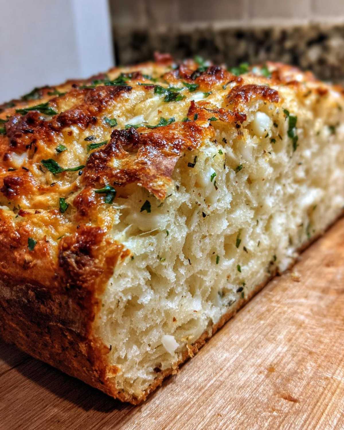 Close-up of a freshly baked loaf of Italian herb and cheese bread showing a golden crust and soft interior