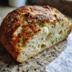 Close-up of a freshly baked Italian herb and cheese bread, showing a soft interior and melted cheese pockets.