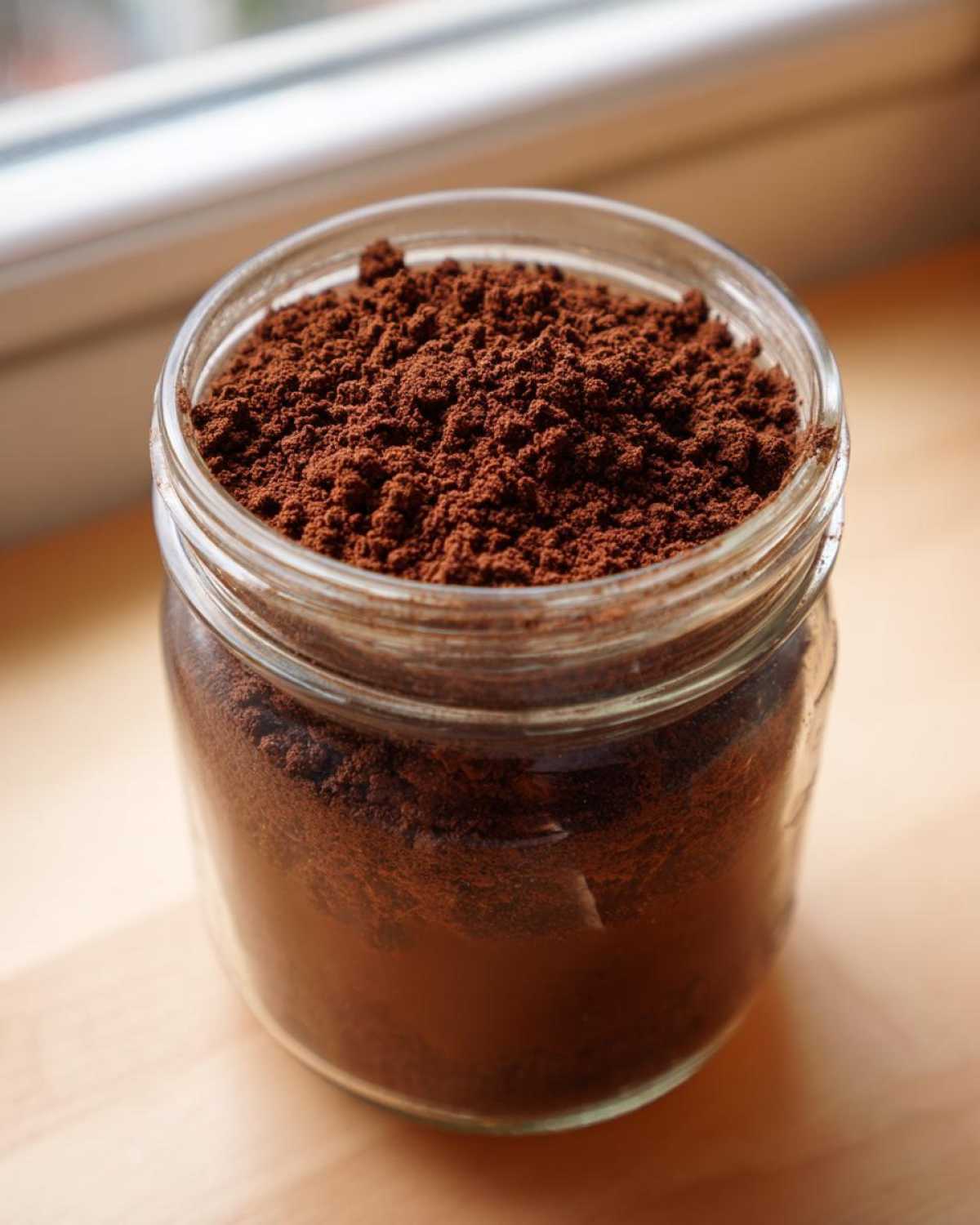 Close-up of a glass jar filled with rich, dark brown homemade hot cocoa mix powder.