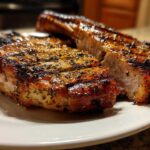 Close-up of two thick, grilled pork chops showing a caramelized crust and juicy interior, perfect for a marinade for pork chops.