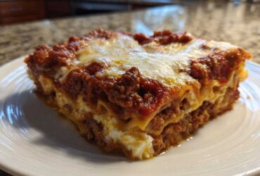A thick, square slice of Lasagna with Cottage Cheese showing layers of pasta, meat sauce, and white cheese filling.