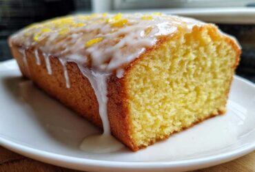 Close-up of a moist lemon pound cake loaf topped with white glaze and lemon zest.