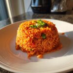 A mound of bright orange Spanish rice, garnished with green onions, served on a white plate.