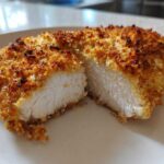 Close-up of a juicy parmesan crusted chicken breast cut in half, showing the white interior and golden crust.