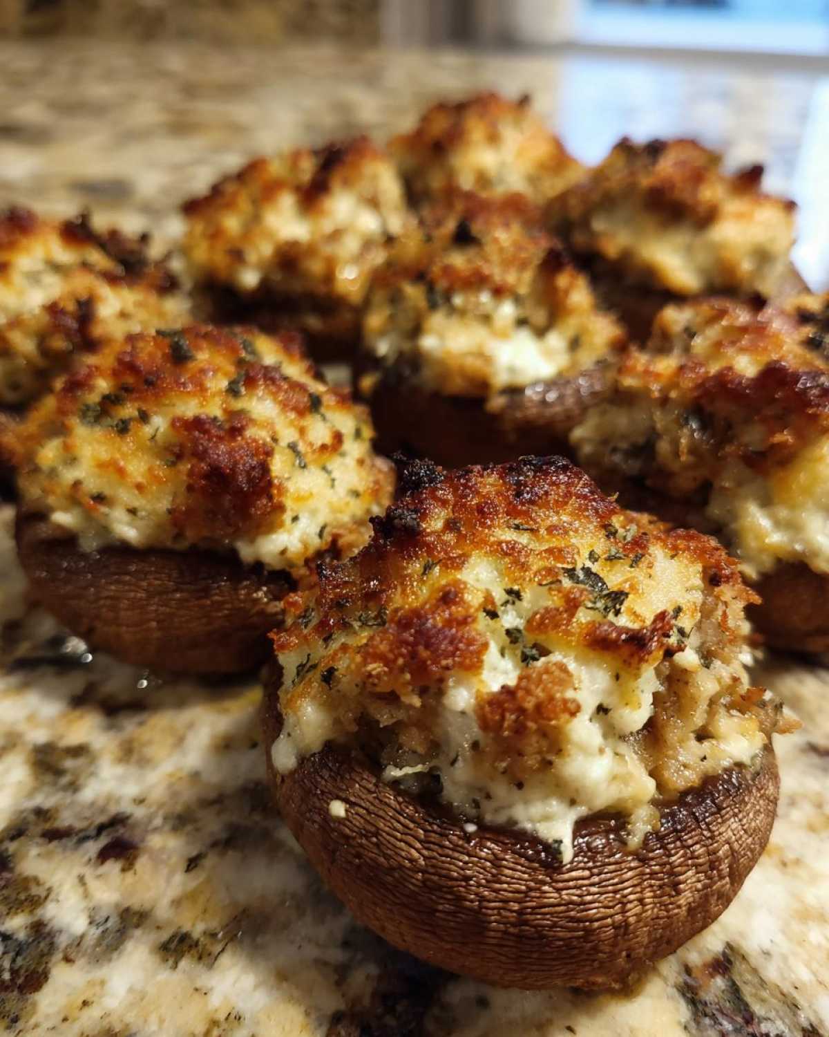 Close-up of freshly baked sausage stuffed mushrooms with a golden, cheesy, herbed topping.