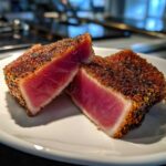 Two thick slices of perfectly Seared Ahi Tuna, showing a deep pink rare center and a dark, seasoned crust.