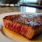 Close-up of a perfectly seared, medium-rare tuna steak resting in its juices, showing the result of a great MARINADE FOR TUNA STEAK.