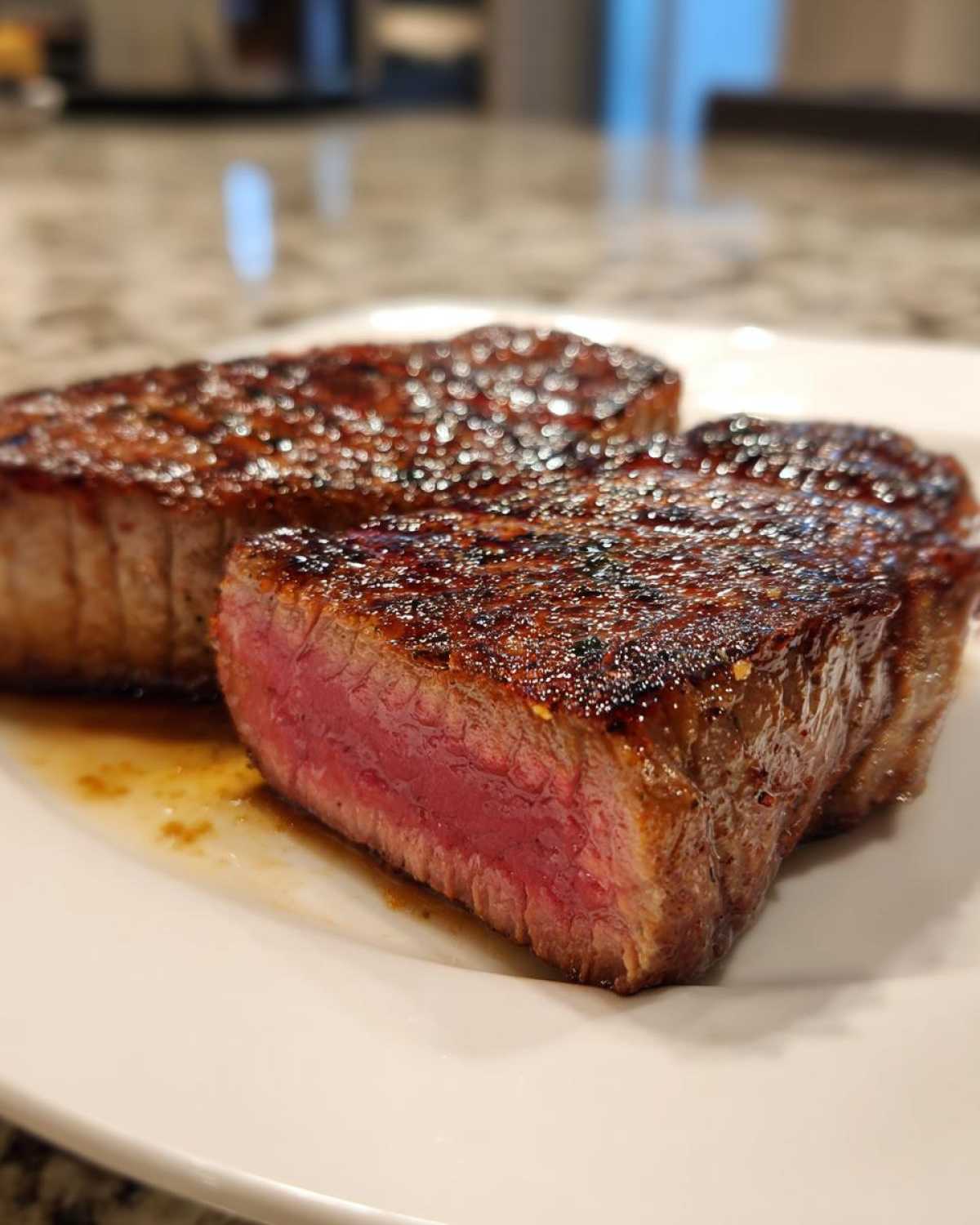 Close-up of two perfectly seared steaks, sliced to show a vibrant medium-rare interior, likely after using the MARINADE FOR TUNA STEAK recipe.