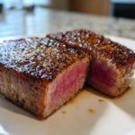 Close-up of a perfectly seared tuna steak, cut in half to show a rare, pink center, ideal for a MARINADE FOR TUNA STEAK recipe.