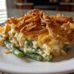 A close-up serving of creamy green bean casserole topped generously with golden, crispy fried onions.