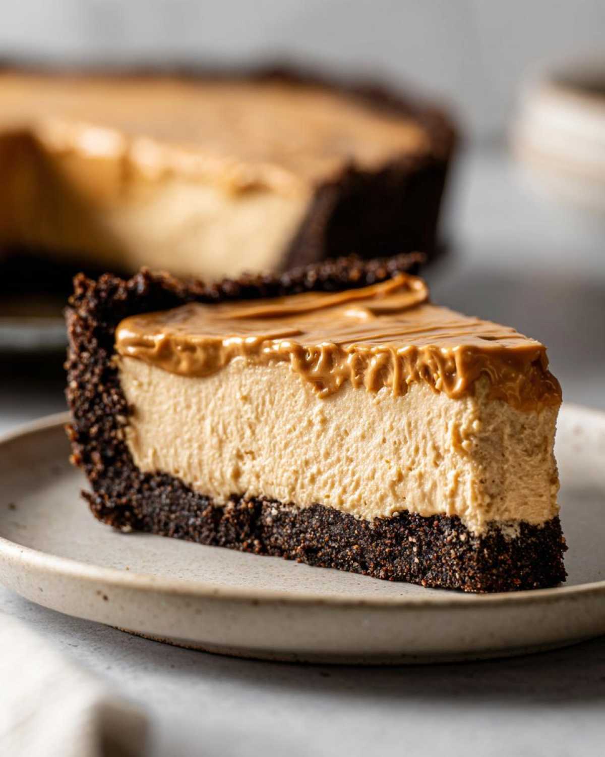 A thick slice of creamy peanut butter pie with a dark chocolate crust, topped with a swirl of peanut butter.