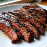 Close-up of perfectly grilled and sliced steak showing a medium-rare interior, seasoned with the Carne asada marinade.