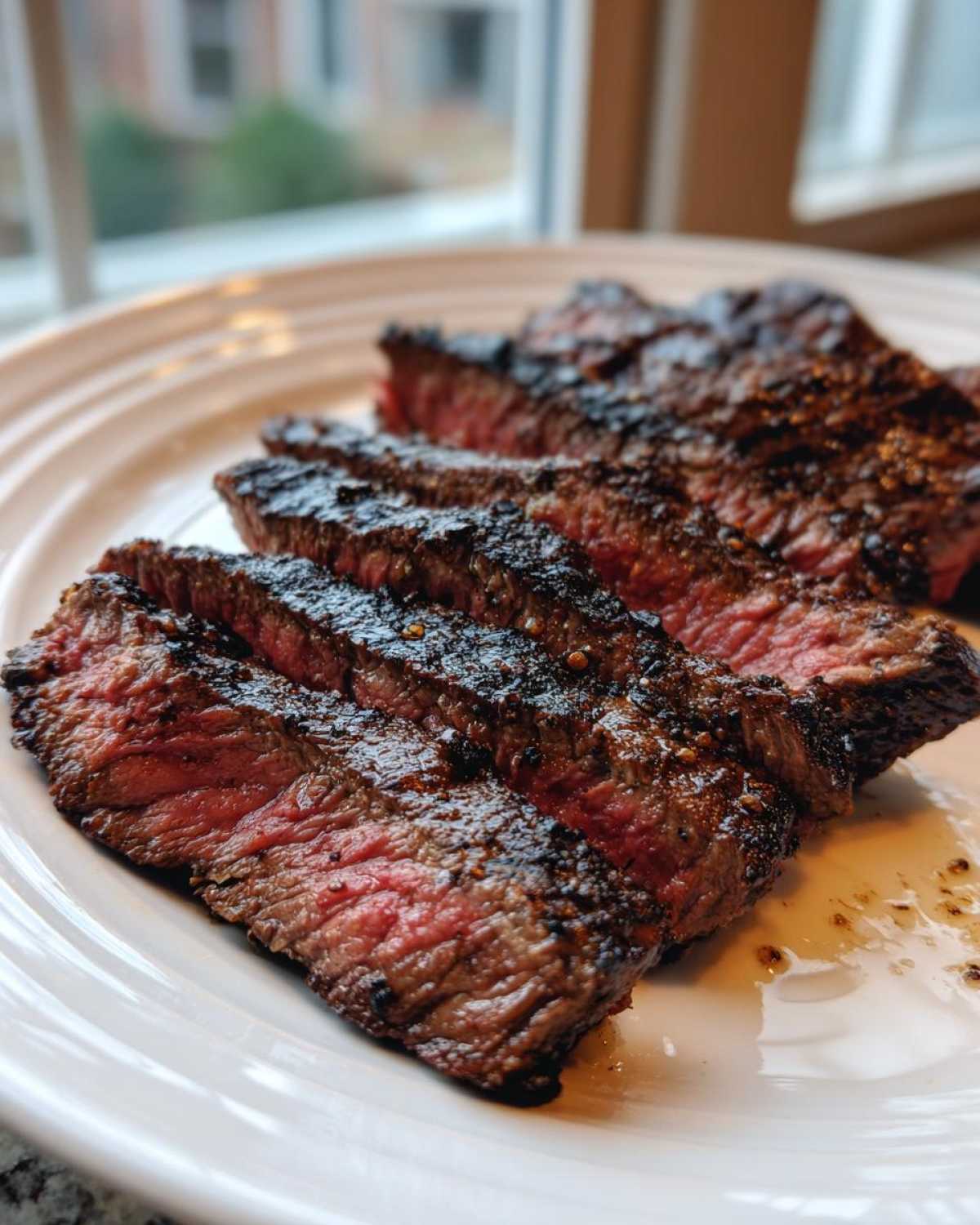 Slices of medium-rare steak showing a dark sear, likely prepared with a Carne asada marinade.