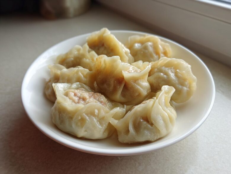A white plate filled with several freshly steamed Traditional Chinese Dumplings, showing the savory meat filling.
