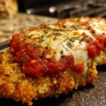 Close-up of a golden, breaded Air Fryer Chicken Parmesan topped with melted mozzarella and marinara sauce.