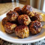 A close-up of several perfectly browned Air Fryer Italian Meatballs piled high on a white plate.
