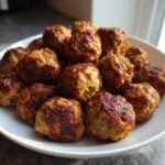 A white plate piled high with freshly cooked, browned Air Fryer Italian Meatballs.