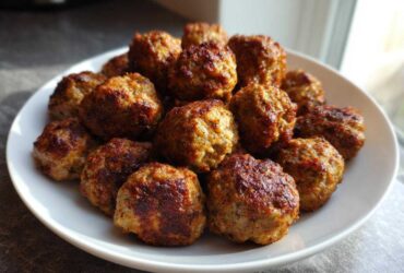 A white plate piled high with freshly cooked, browned Air Fryer Italian Meatballs.