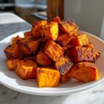 A white bowl filled with perfectly cooked, caramelized Air Fryer Sweet Potato Cubes, showing crispy edges.