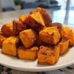 A white plate piled high with golden brown, crispy Air Fryer Sweet Potato Cubes.