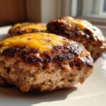 Close-up of three juicy Air Fryer Turkey Burgers topped with melted cheddar cheese on a white plate.