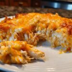 A scoop of creamy, cheesy Baked Buffalo Chicken Dip showing shredded chicken and melted orange cheddar cheese topping.