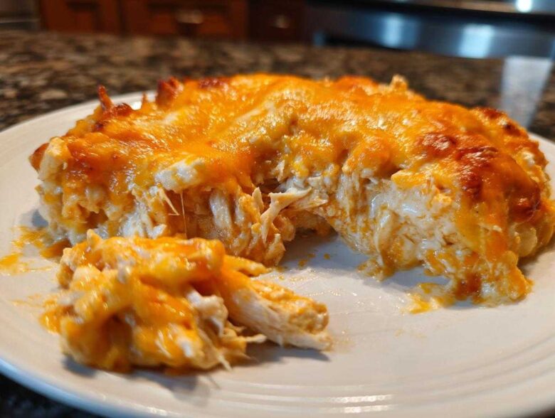 A scoop of creamy, cheesy Baked Buffalo Chicken Dip showing shredded chicken and melted orange cheddar cheese topping.