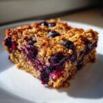 Close-up of a single, moist square of Blueberry Baked Oatmeal Squares on a white plate.