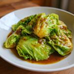 Bright green cabbage wedges coated in a rich garlic ginger sauce, served in a white bowl as part of a Cabbage Stir Fry.