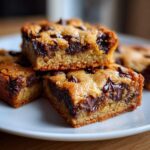 Close-up of three stacked Chewy Chocolate Chip Cookie Bars showing gooey melted chocolate chips.