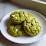 A stack of three Chewy Matcha White Chocolate Cookies with visible white chocolate chips on a white plate.
