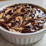 Close-up of Chocolate Peanut Butter Cheesecake Dip swirled with rich chocolate topping in a white dish.