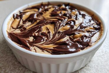 Close-up of Chocolate Peanut Butter Cheesecake Dip swirled with rich chocolate topping in a white dish.