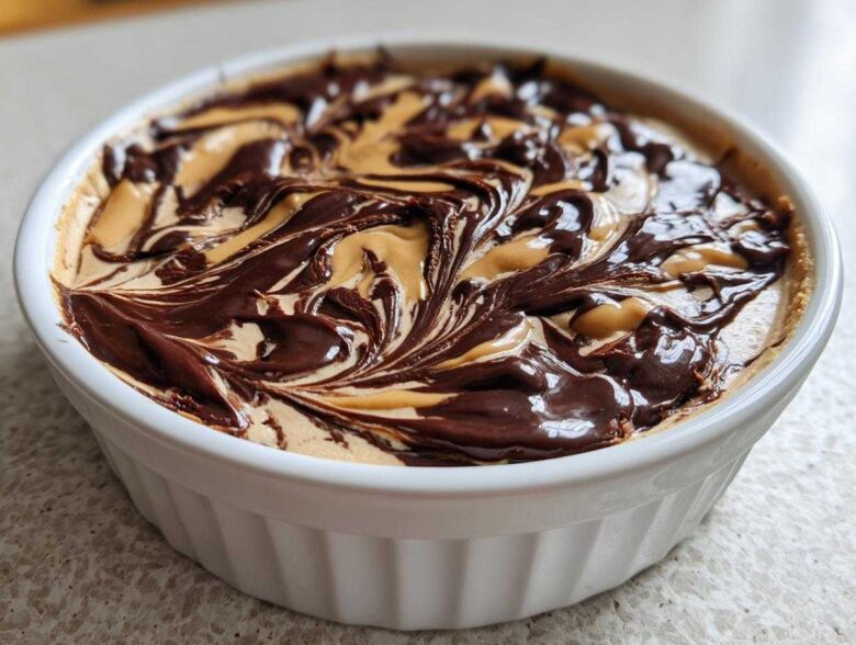 Close-up of Chocolate Peanut Butter Cheesecake Dip swirled with rich chocolate topping in a white dish.