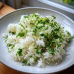 A serving of fluffy white Cilantro Lime Rice topped generously with fresh chopped cilantro and bright green lime zest.