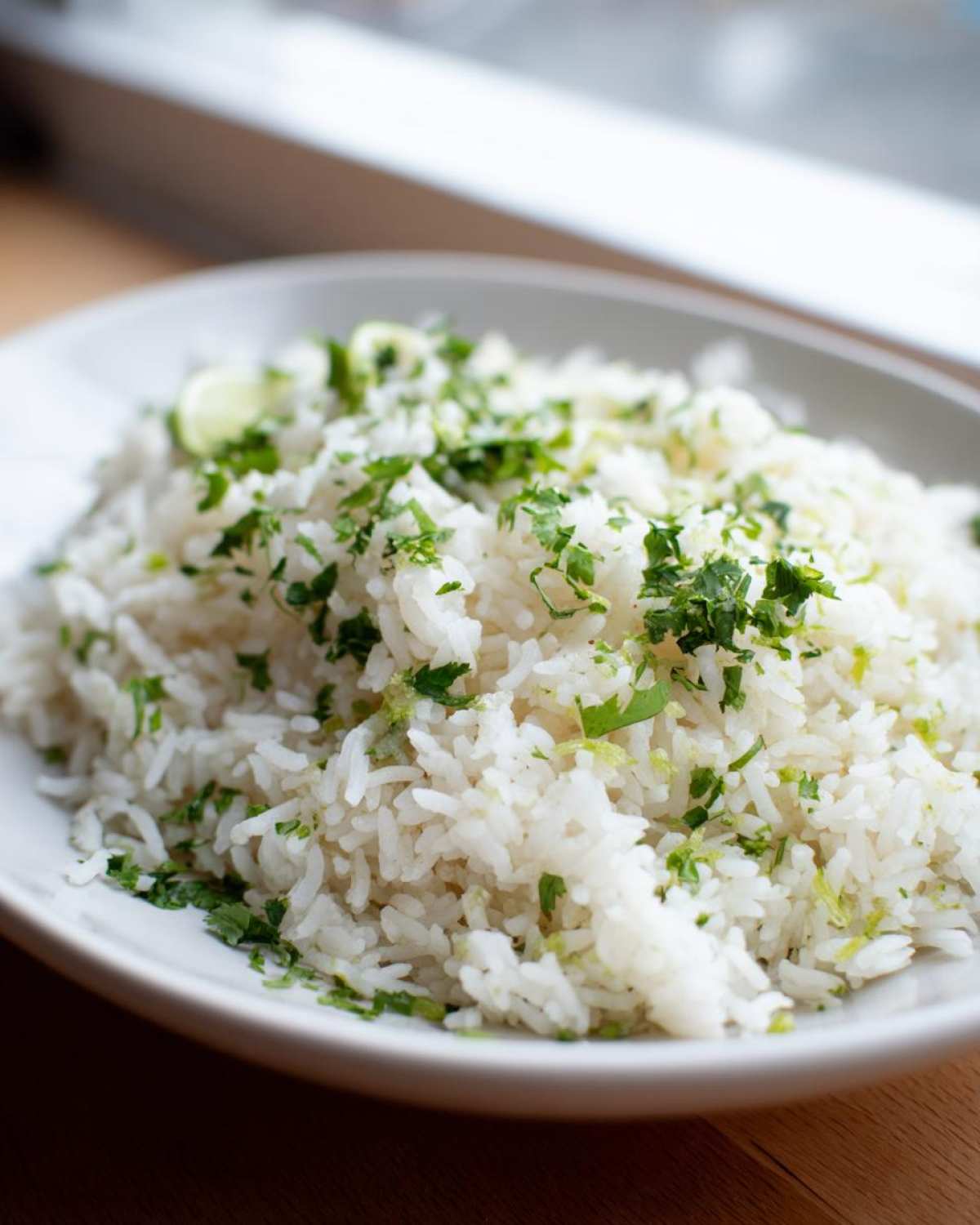 A close-up of fluffy white Cilantro Lime Rice topped with fresh chopped cilantro and lime zest.