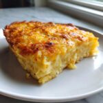 A golden-brown slice of Copycat Cracker Barrel Hashbrown Casserole on a white plate.