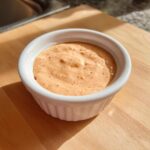 Close-up of Copycat Raising Cane’s Sauce in a small white ramekin on a wooden surface.