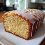 A moist slice of Copycat Starbucks Iced Lemon Loaf with thick white glaze and lemon zest topping.