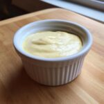 Close-up of creamy, yellow Copycat Taco Bell Chicken Quesadilla Sauce in a white fluted ramekin.