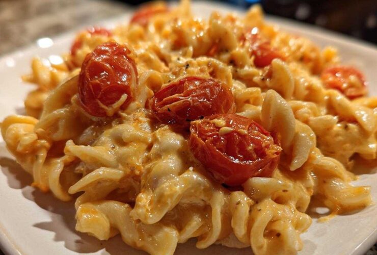 Close-up of creamy Baked Feta Pasta with fusilli noodles coated in orange sauce and topped with roasted cherry tomatoes.