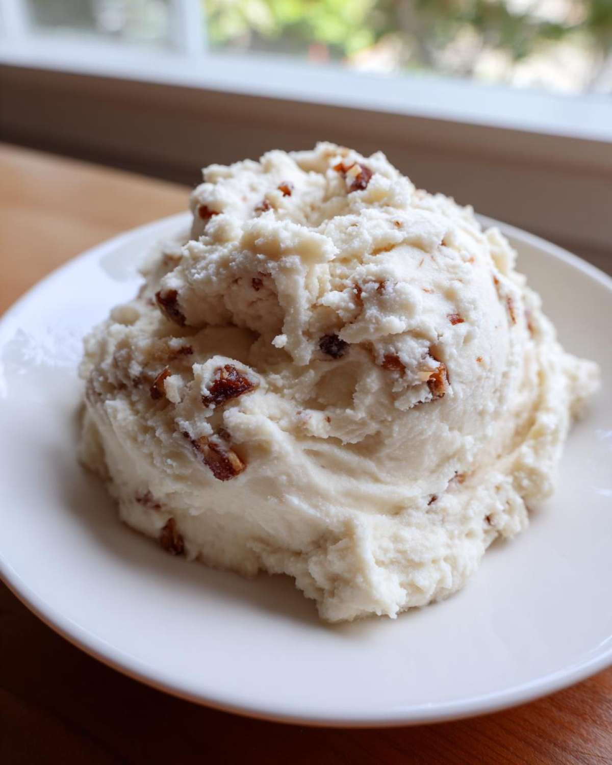 A scoop of Creamy Garlic Mashed Cauliflower topped with browned bits, served on a white plate.