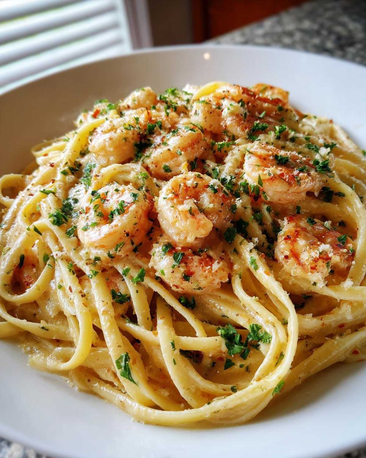 A close-up of Creamy Lemon Garlic Shrimp Pasta featuring linguine coated in a rich sauce, topped with seasoned shrimp and fresh parsley.