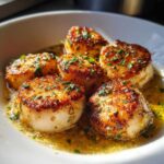 Close-up of seared Garlic Butter Scallops with Lemon, glistening in a buttery sauce and topped with parsley.