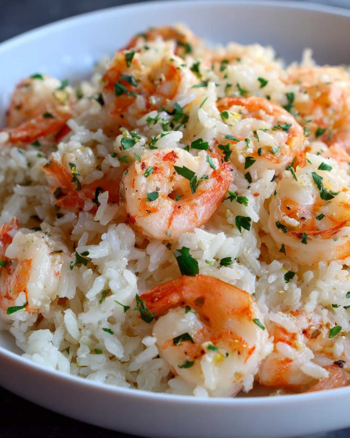 Close-up of juicy shrimp mixed with white rice, garnished with fresh parsley, from the Garlic Butter Shrimp and Rice Skillet.