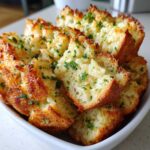 Close-up of baked Garlic Parmesan Pull-Apart Bread pieces stacked in a white bowl, topped with melted cheese and parsley.