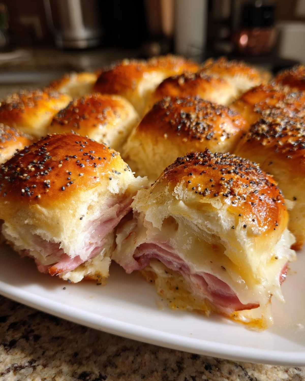 A close-up view of Hawaiian Roll Ham and Cheese Sliders, showing one slider pulled apart revealing melted cheese and ham.